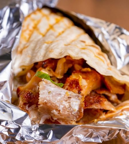 About Us Tasty chicken shawarma wrapped in flatbread and foil, ready to enjoy.